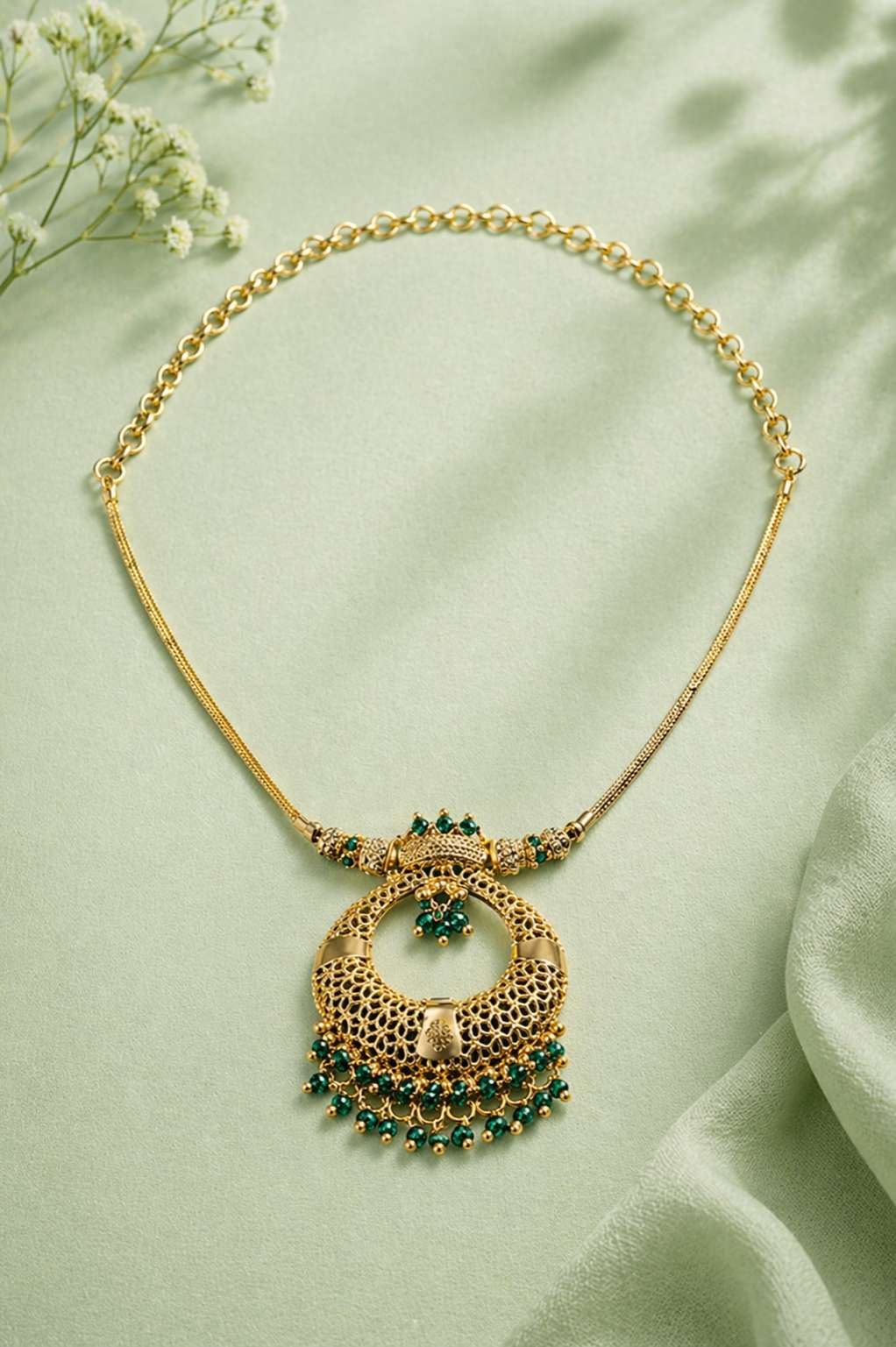 Ornate gold necklace with green gemstones